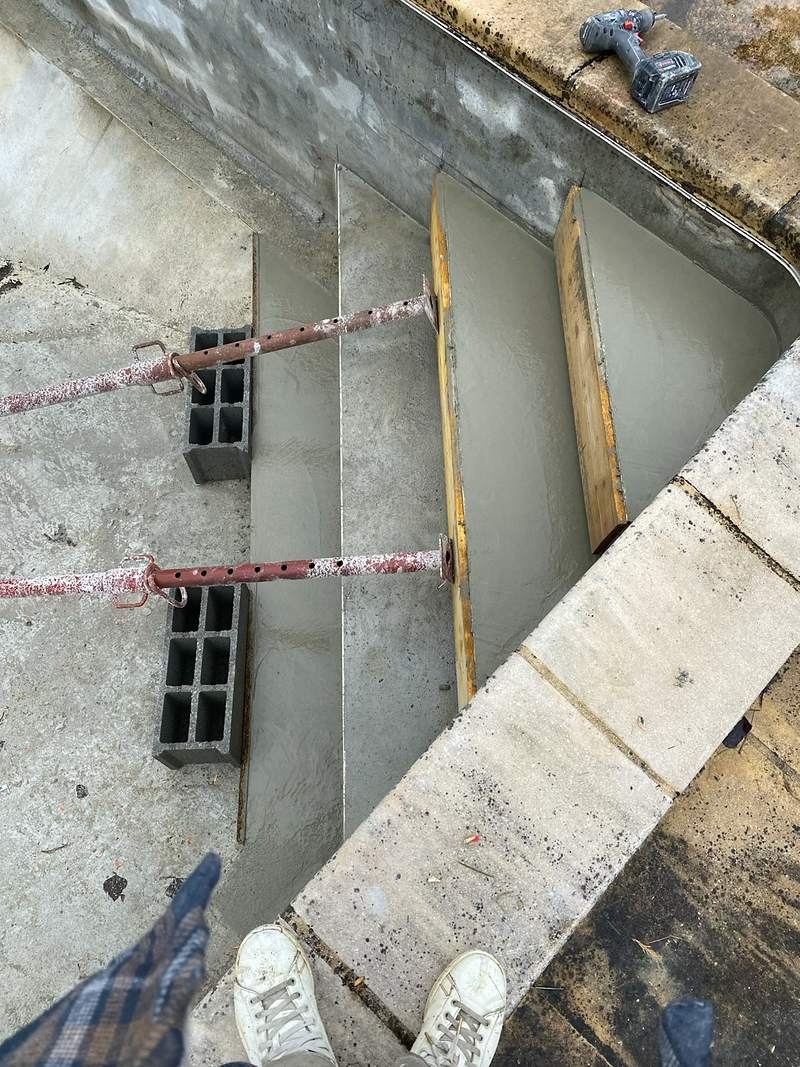 Coffrage des marches d'un escalier de piscine maintenu par des étais pendant le coulage du béton à Grenade