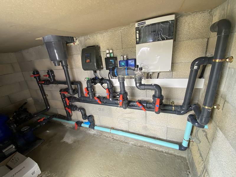 Local technique de piscine avec nourrices de vannes et électrolyseur, mai 2026