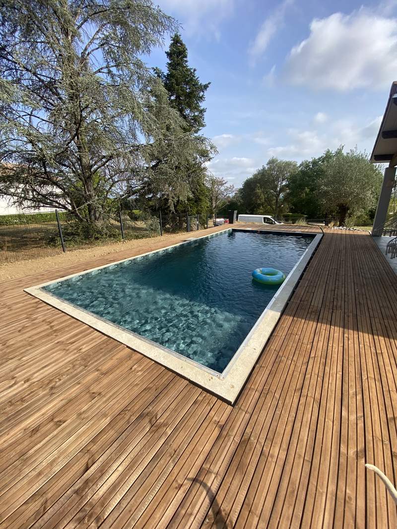 Bassin rectangulaire en membrane armée entouré d'une terrasse en bois à Castelnau-d'Estrétefonds, août 2026