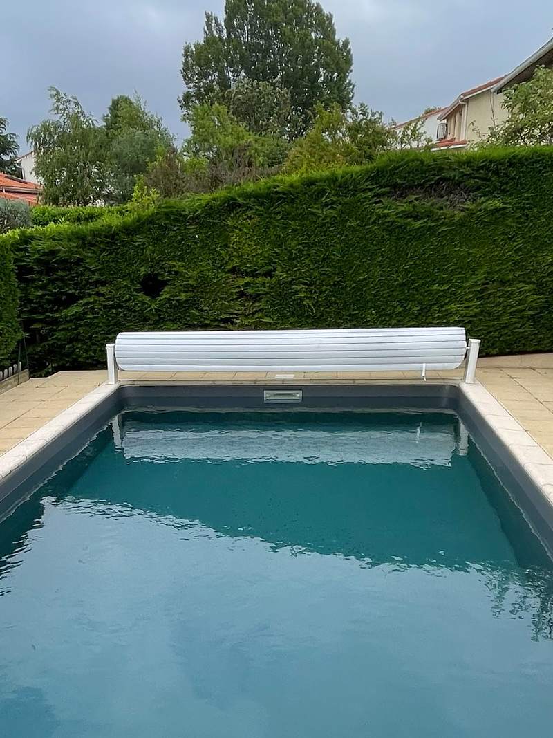 Volet roulant hors-sol sur une piscine au revêtement gris anthracite